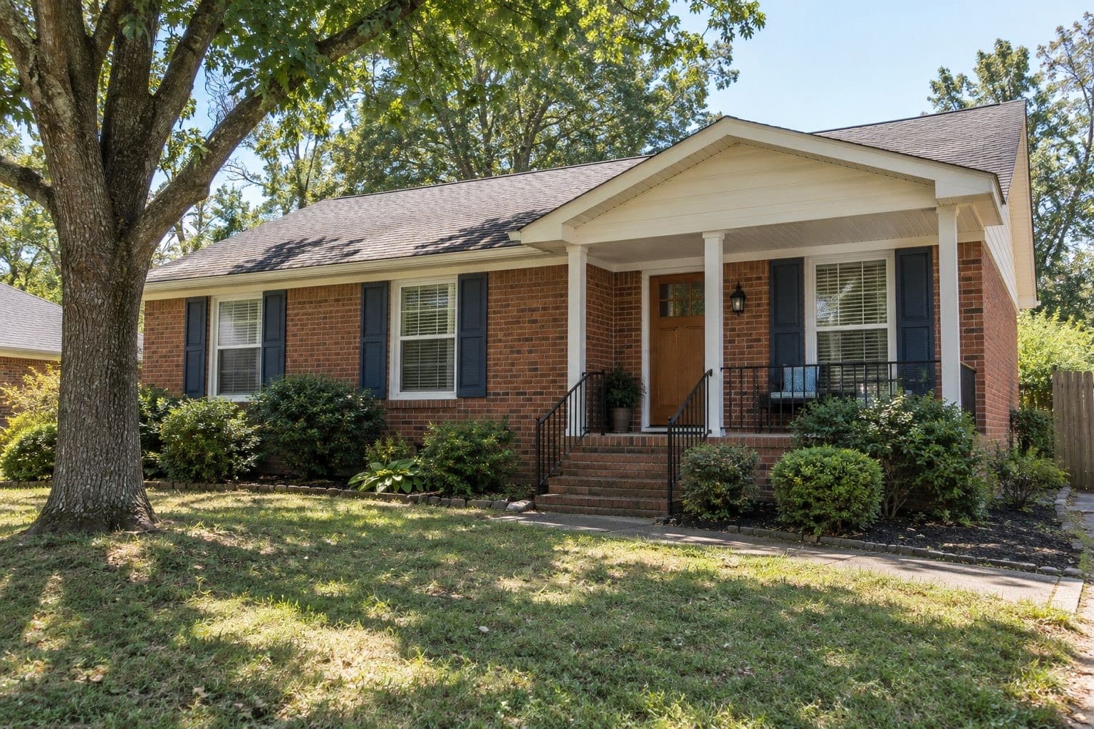 Brick ranch home with navy shutters and white porch columns