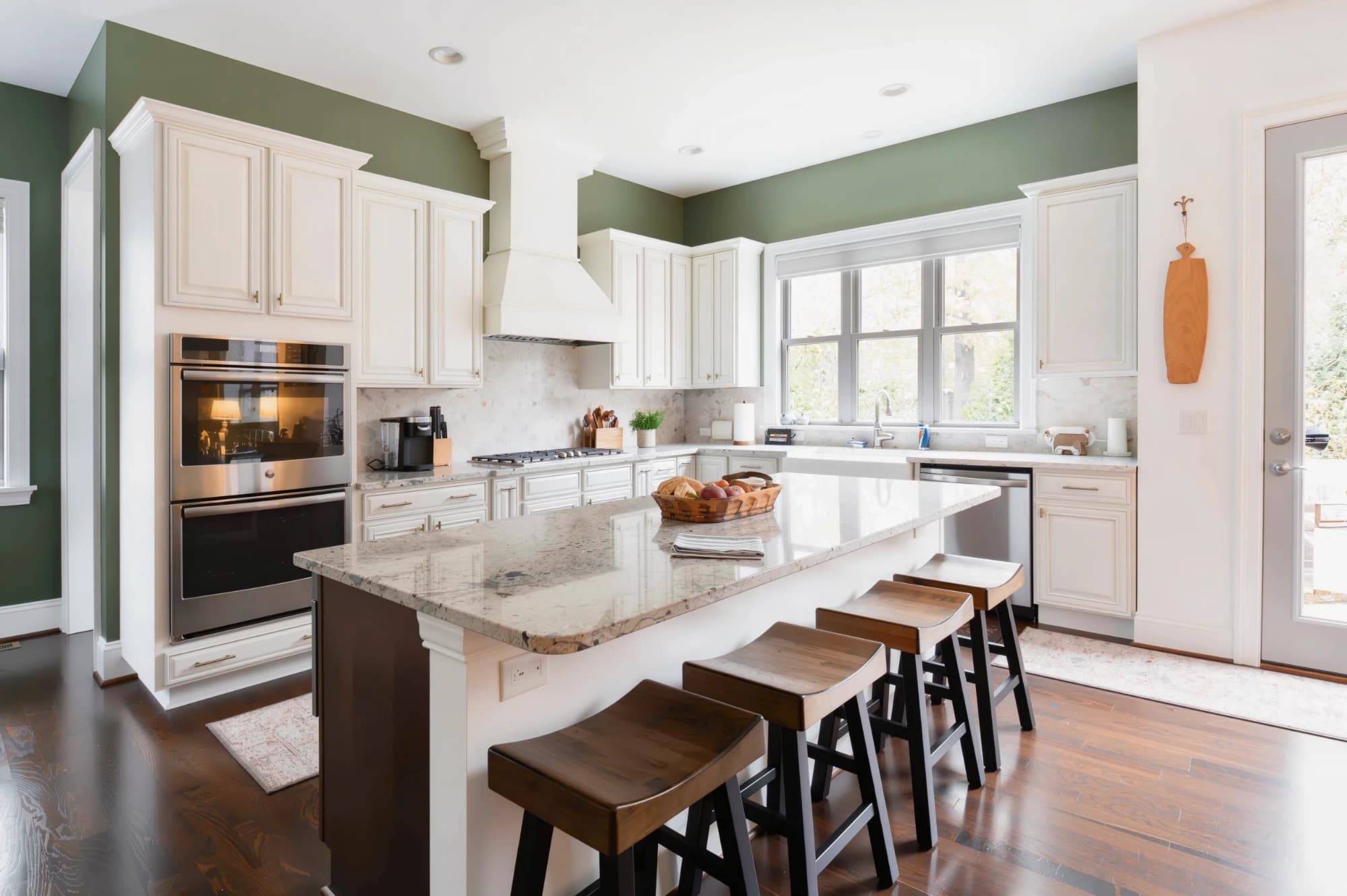 Kitchen with freshly painted white raised-panel cabinets, sage green walls and a granite island