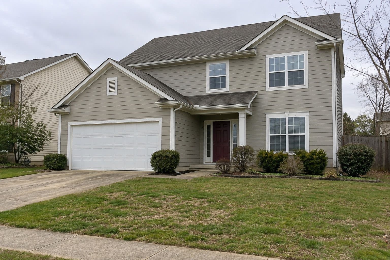 Two-story home with greige siding, white trim and a burgundy front door